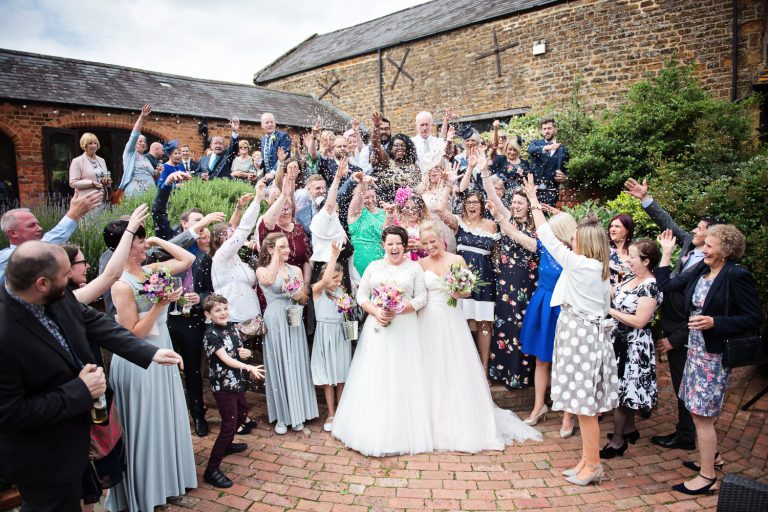 Wedding guests shower the bride and bride with confetti in the courtyard of Dodmoor House.