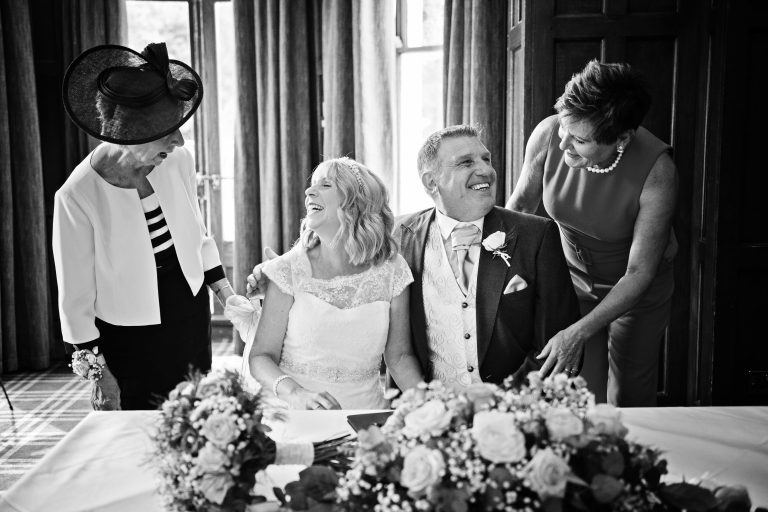 B&W image of two wedding witnesses congratulating bride and groom.