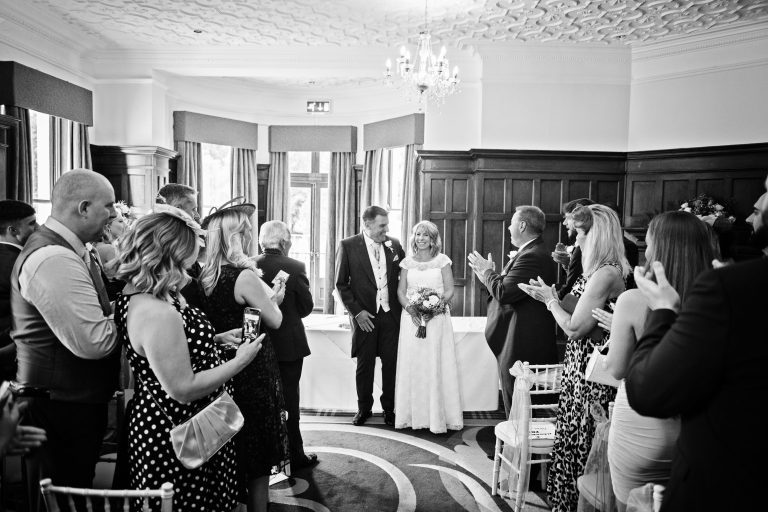 B&W photo of a newly married couple at the end of their wedding ceremony at Double Tree Hilton, Charlton Kings.
