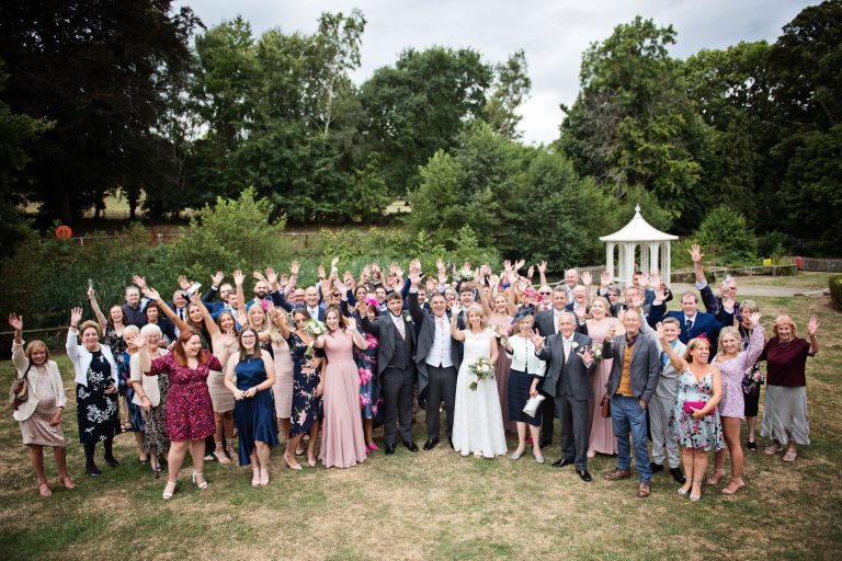 Large group shot of wedding guests smiling and waving at Double Tree Hilton.