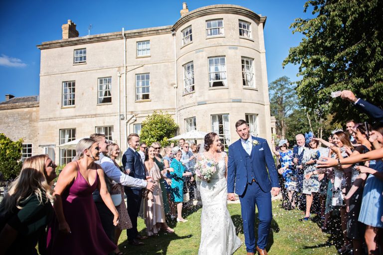 Bride & Groom walking through their guests whilst confetti is being thrown at them at Eastington Park