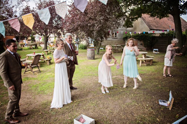 Candid photo of bride and groom playing garden games with their friends and family.