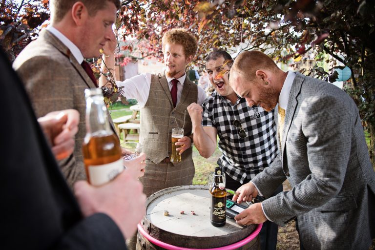 Documentary candid photo of games being played at a wedding by the groom and his groomsmen.