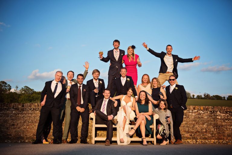 Wedding guests make most of the golden hour by sitting on a bench and wall.
