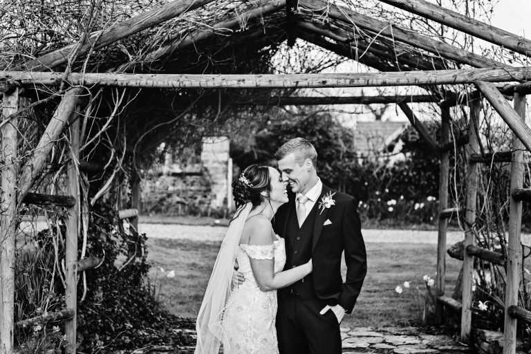 B&W photo of bride and groom grabbing a moment together at Great Tythe Barn