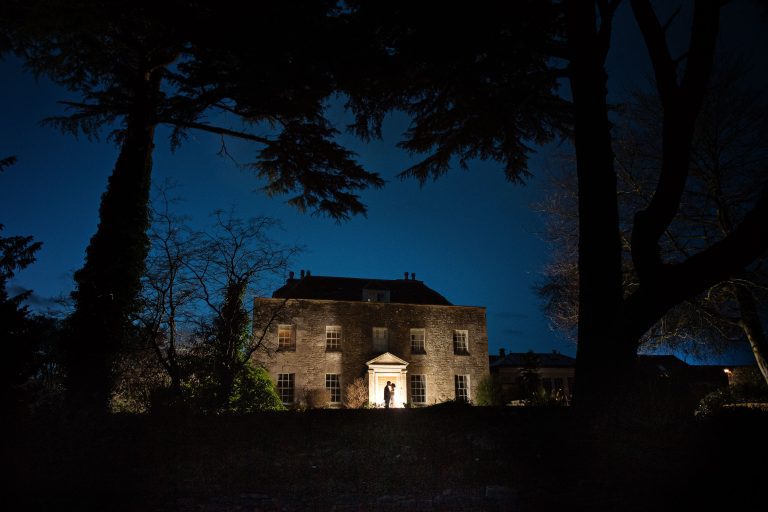 Night time shot at Great Tythe Barn house with bride and groom lit up.