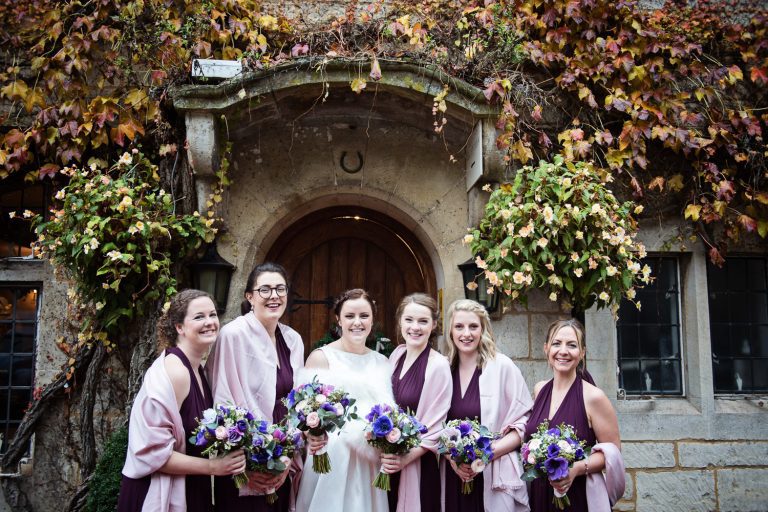 Bride and bridesmaids stand in front of the main door.