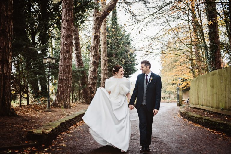 Bride and groom walk hand in hand down the drive at Hatton Court Hotel.