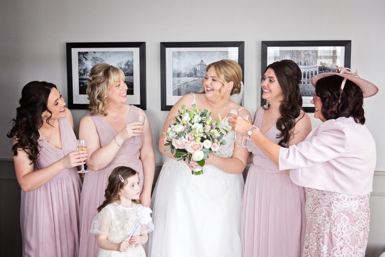 Bride and her mum and bridesmaids raise a glass of fizz after getting ready for the wedding at Hatton Court Hotel.