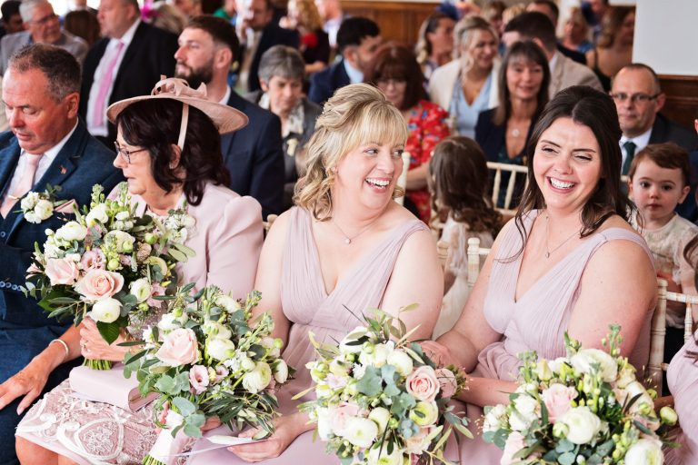 Bridesmaids smiling and laughing whilst they hold their wedding bouquets.