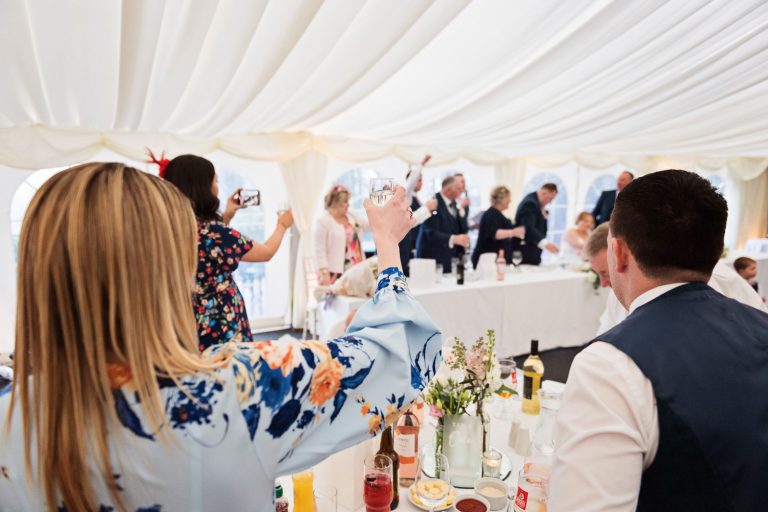 Wedding guests raise a glass at the end of speeches at Hatton Court Hotel.