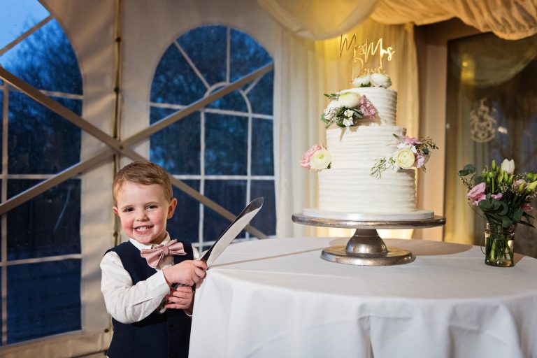 Fun image of a page boy about to cut the wedding cake at Hatton Court.