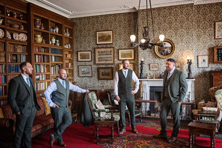 Groomsmen stand posing but not posing in the library at Homme House.