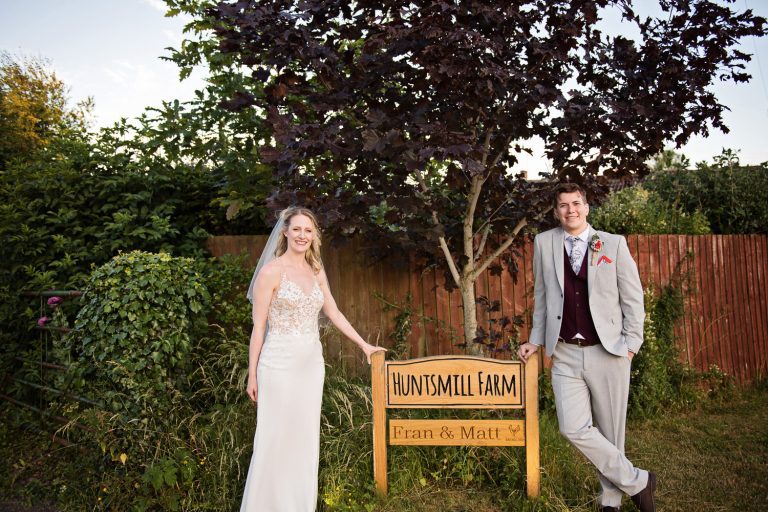 Bride and groom stand in front of the Huntsmill Farm.