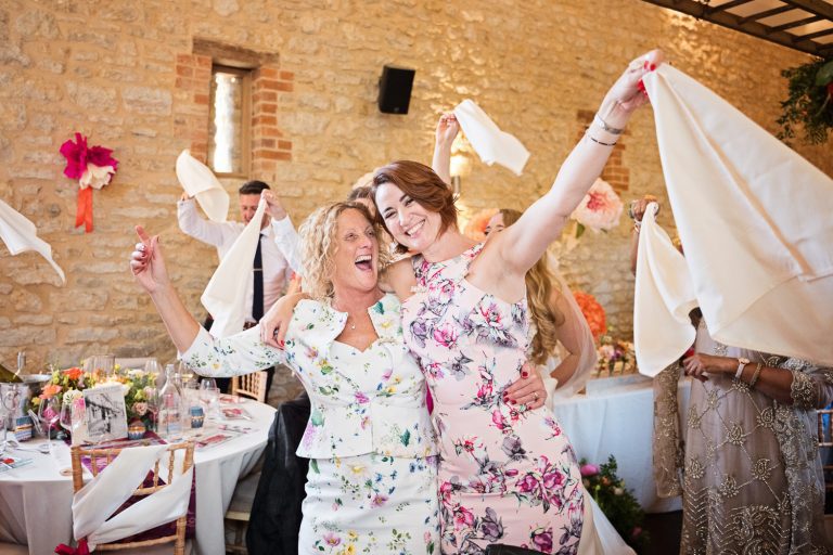 Fun picture of wedding guests having a good time whilst waving their napkins.