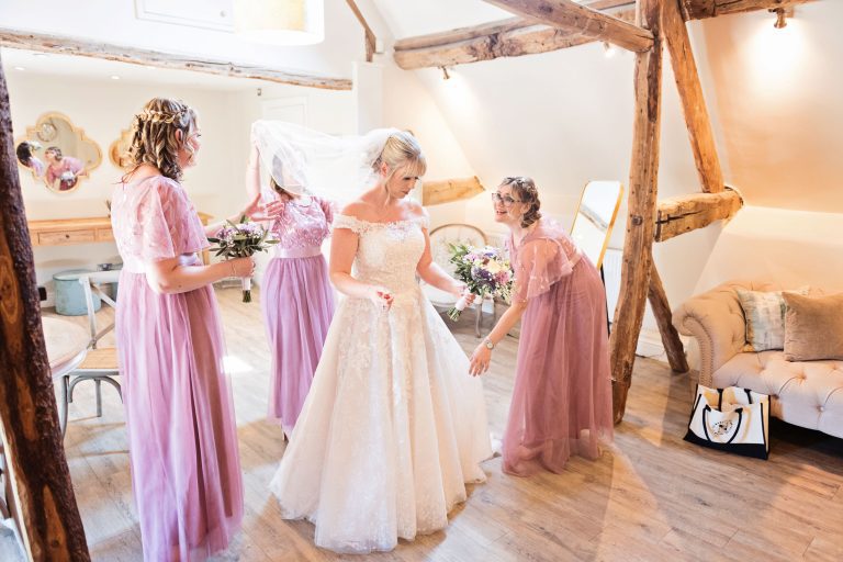 Bride with her bridesmaids making final adjustments.