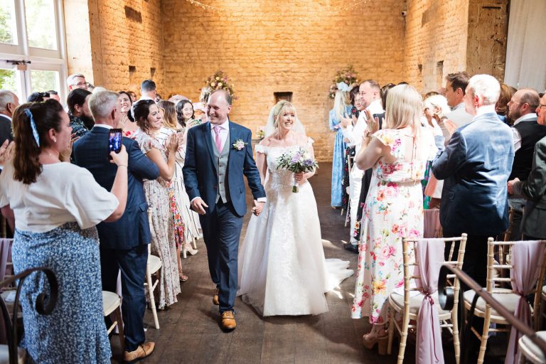 Bride and groom exit the ceremony barn with their friends and family congratulating them after getting married at Lapstone Barn.