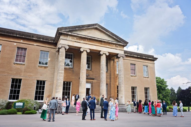 Exterior photograph of Leigh Court, Bristol with wedding guests chatting informally before a wedding.