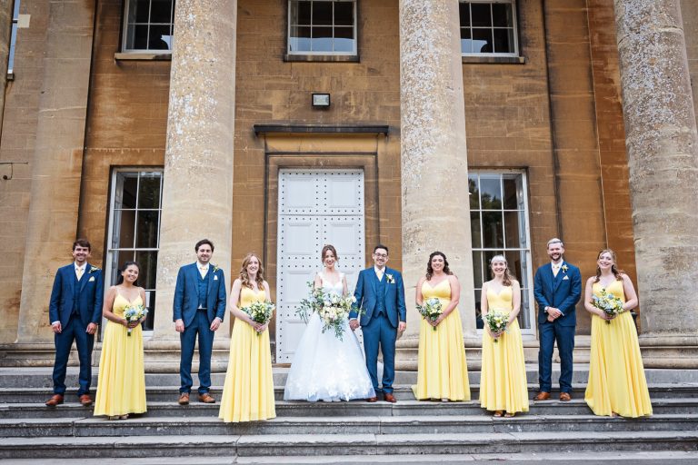 Bridal party standing on the steps of Leigh Court. Leigh Court has large stone pillars.