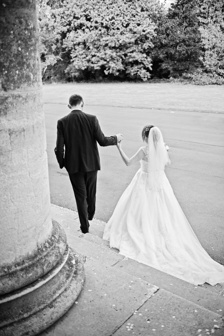 B&W portrait photo of bride and groom walking away from camera down the steps of Leigh Court.