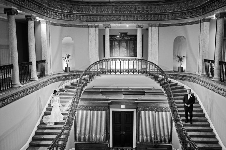 B&W photo of the magnificent ornate double stairs with the bride and groom standing either side.