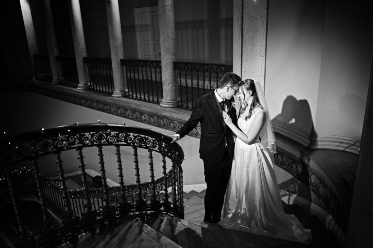 B&W photo og a bride and groom at the top of the ornate stairs at Leigh Court.