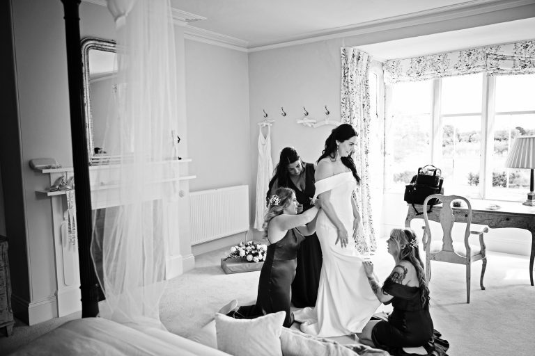 B&W photo of bride getting ready, helped by her bridesmaids. Set in a Georgian bedroom.