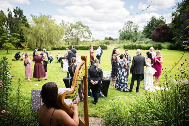 Lovely photo of a harpist plating in the gardens whilst the wedding reception goes on.