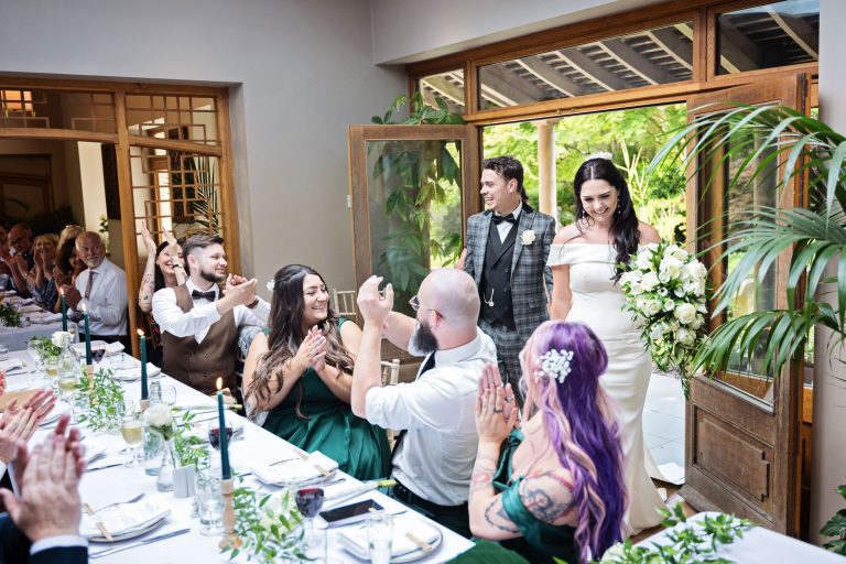 Bride and groom enter the wedding breakfast with claps and cheers from their wedding guests.