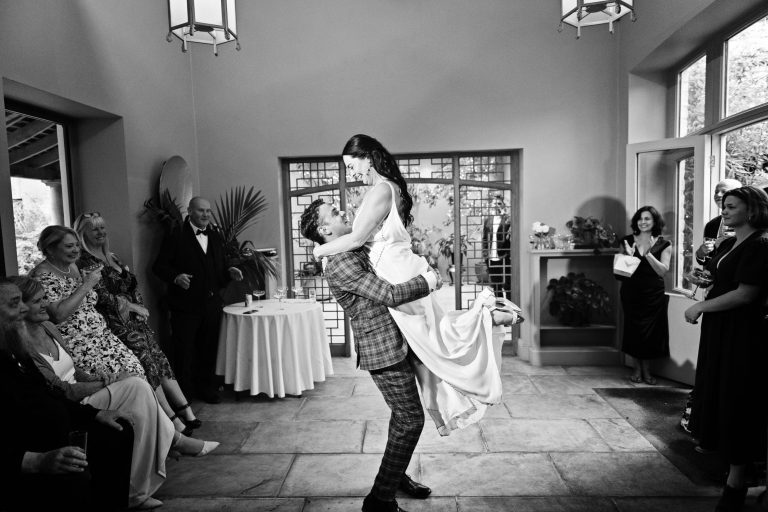 The groom picks up his bride during the first dance. B&W.