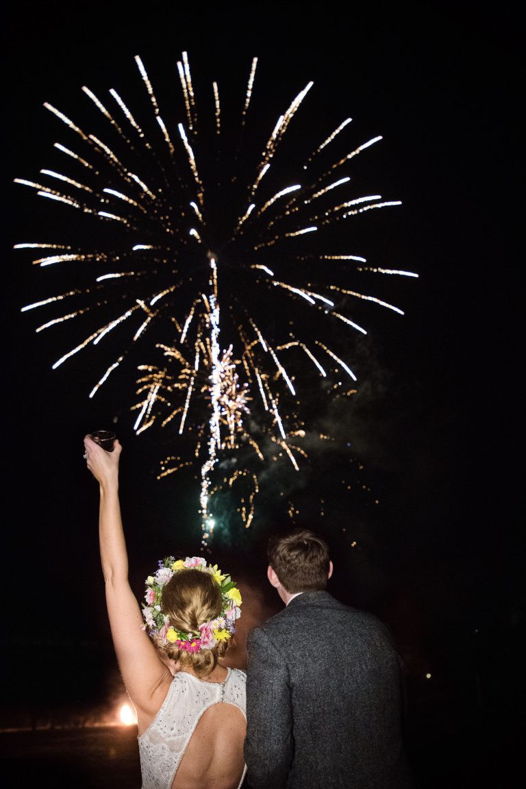 Bride and groom look onwards at impressive fireworks.