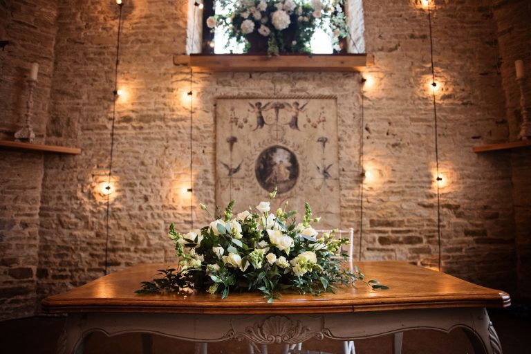 Wedding table set up for a wedding ceremony at Merriscourt. Stone walls and lights and wedding flowers and old art make this look magical.