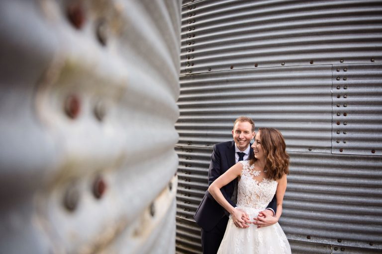 Bride and groom in between the middle of the exterior of the silos. Silos curve towards them in a arty way.