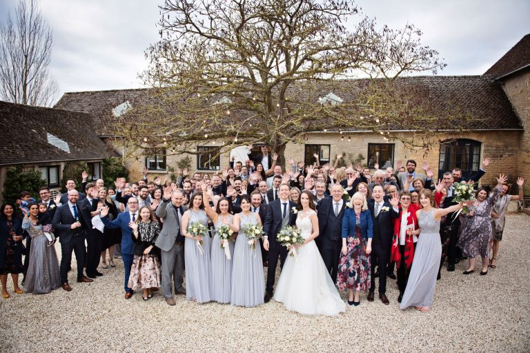 Large fun group shot of everyone (inc bride & groom)at the wedding in the courtyard at Merriscourt