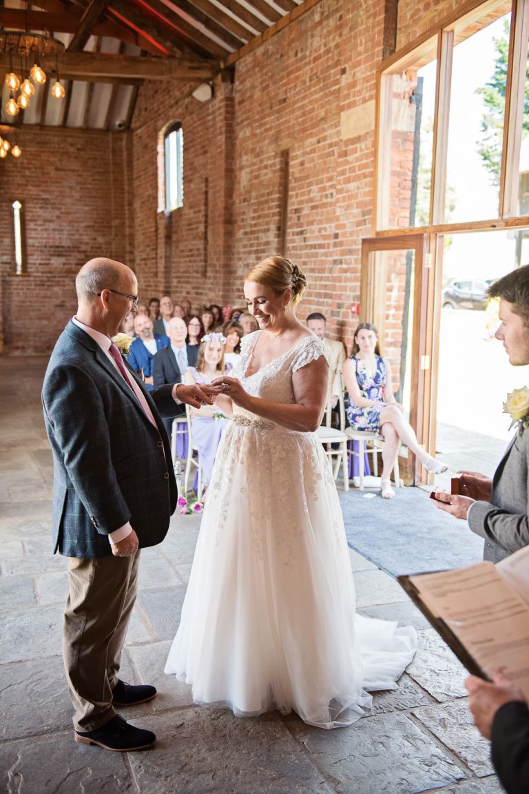 Portrait photo of bride and groom exchanging wedding rings during their wedding ceremony.