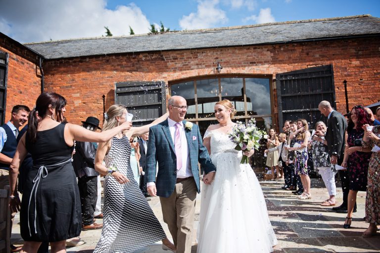 Bride and groom getting showered by confetti at their wedding at Mickleton Hills Farm.