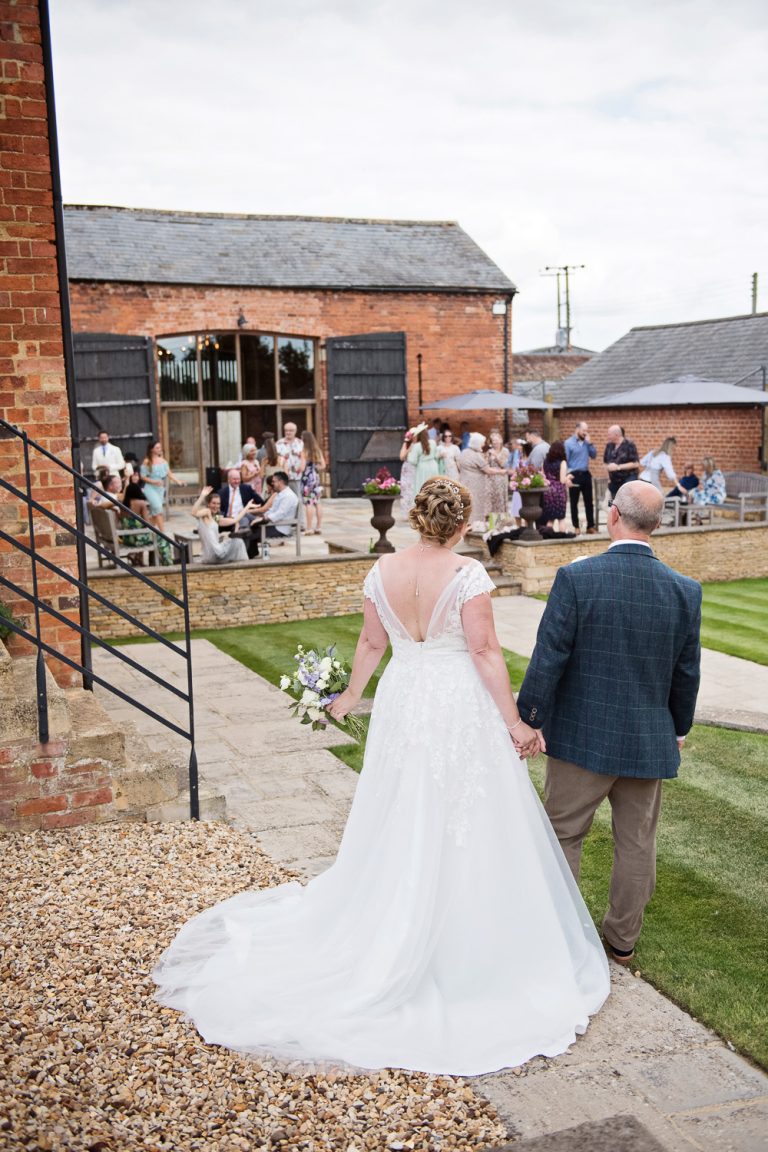 Back of bride and groom as they look towards their wedding guests at Mickleton Hills Farm.