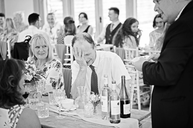 B&W candid photograph of a guest putting his hand on his face after being wowed by the Gloucestershire Magician, Richard Parsons.
