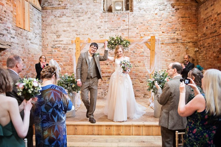 Bride and groom finish their wedding ceremony with the guests clapping.