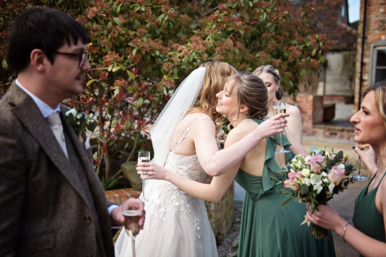 Candid photograph of bride being congratulated by a bridesmaid.