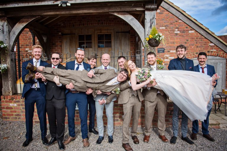 Bride and groom being carried by the grooms friends.
