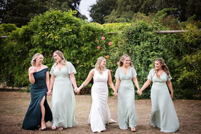 Bride and bridesmaids hold hands.