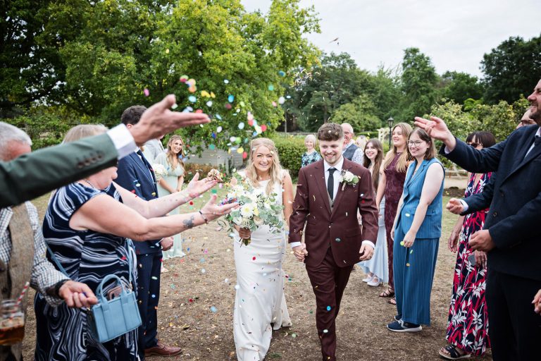 Bride and groom walk in between their wedding guests.