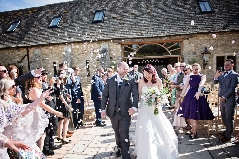 Bride and groom being showered with confetti by their friends and family as they walk back down the wedding isle.