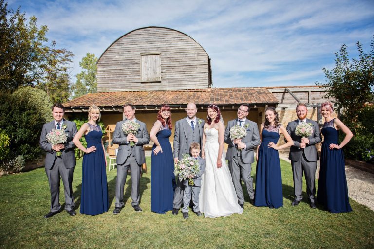 Fun image of bridal party posing together in front of a wedding barn.