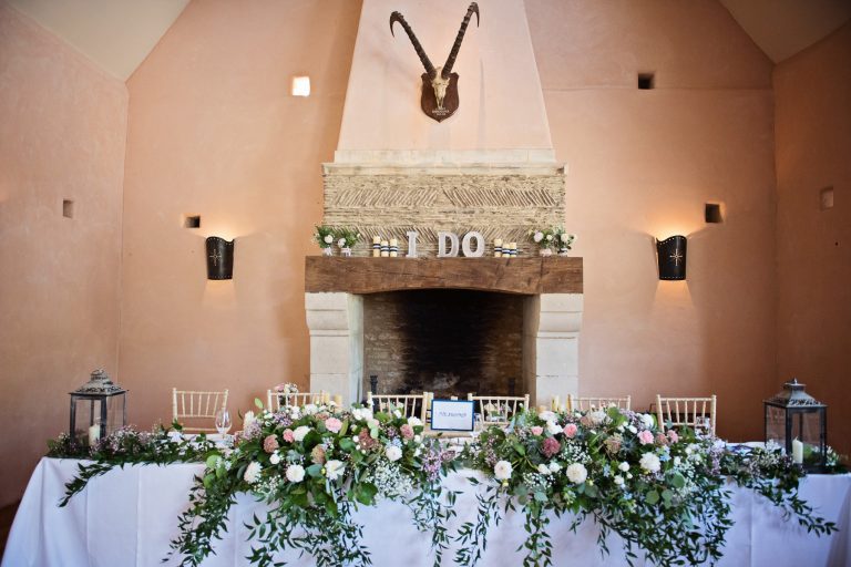 Top table at a wedding breakfast. Gorgeous flowers spread on the table. Fireplace behind.
