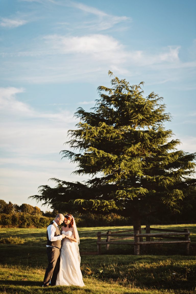 Bride and groom chat in gorgeous Cotswold countryside in golden hour.