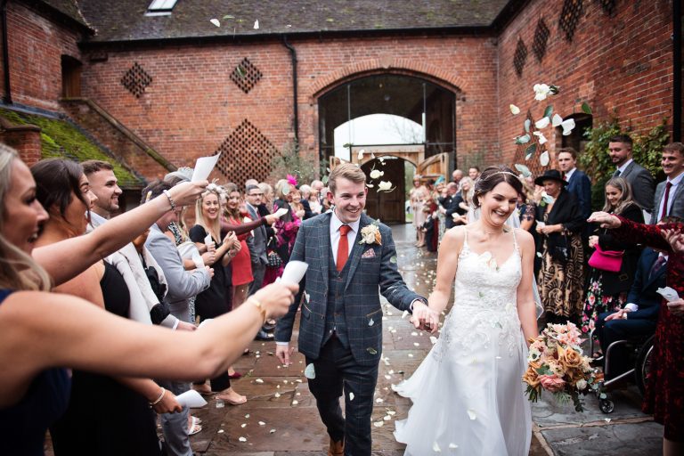 Bride and groom getting showered with confetti by their friends and family.
