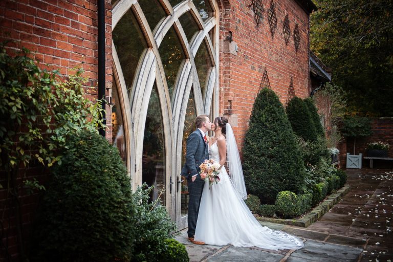 Bride and groom kiss alongside the wedding barn at Shustoke Barn