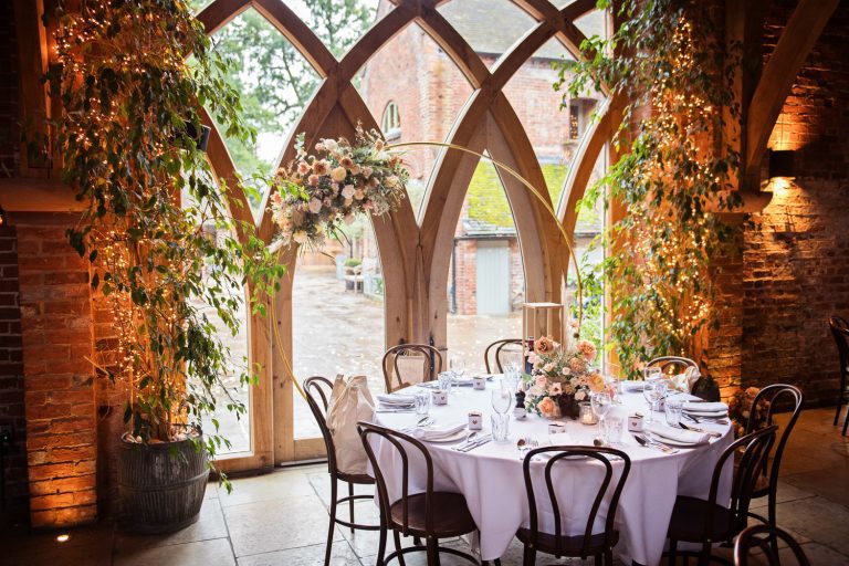 Wedding breakfast table setting with uplighting at Shustoke Barn